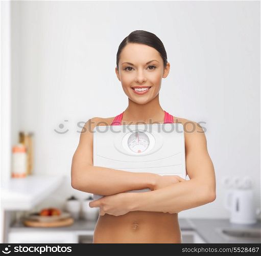 diet and sport concept - beautiful sporty woman with scale in kitchen