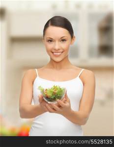 diet and sport concept - healthy woman holding bowl with salad in kitchen