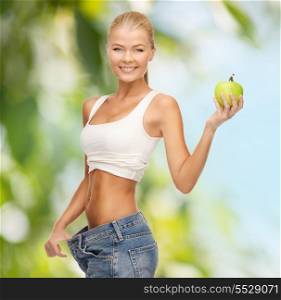 diet and sport concept - picture of sporty woman showing big pants and apple