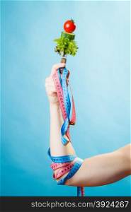 Diet and weight loss concept. Dietician woman hand with vegetarian food and colorful measuring tapes on blue background.