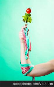 Diet and weight loss concept. Dietician woman hand with vegetarian food and colorful measuring tapes on green blue background.