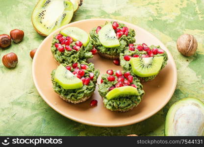 Diet avocado cupcakes garnished with kiwi and pomegranate. Cupcake with avocado cream.