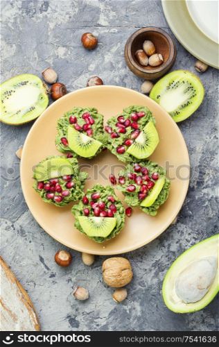 Diet avocado cupcakes garnished with kiwi and pomegranate. Cupcakes from avocado and kiwi.