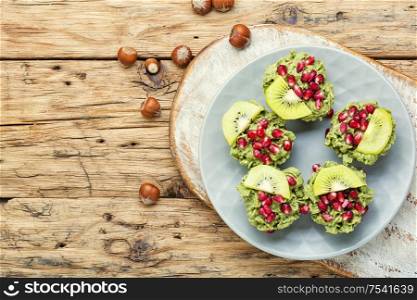 Diet avocado cupcakes garnished with kiwi and pomegranate.Cupcakes on wooden background. Cupcakes from avocado and kiwi.