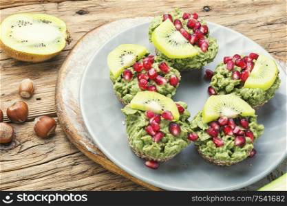 Diet avocado cupcakes garnished with kiwi and pomegranate.Cupcakes on wooden background. Cupcakes from avocado and kiwi.