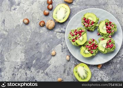 Diet avocado cupcakes or muffin garnished with kiwi and pomegranate.Fairy cake.Space for text. Cupcakes from avocado and kiwi.