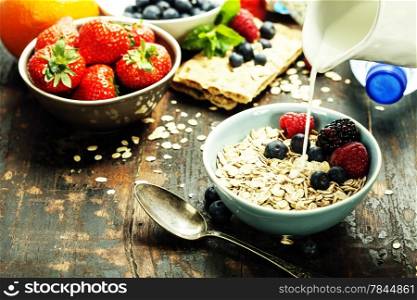 diet breakfast - bowls of oat flake, berries and fresh milk on wooden background - health and diet concept