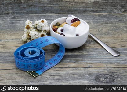 Diet breakfast with granola and yogurt on rustic wooden background.