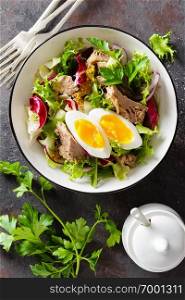 Diet food tuna salad with boiled egg, canned fish, onion and green lettuce top view