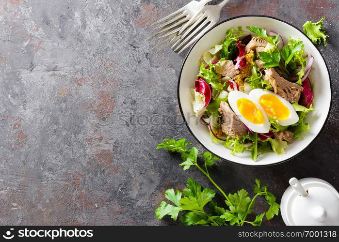 Diet food tuna salad with boiled egg, canned fish, onion and green lettuce top view