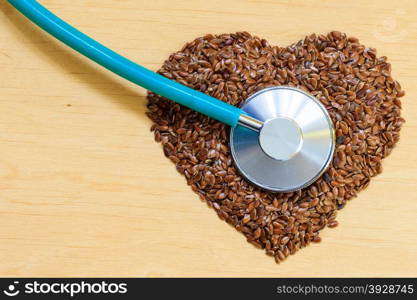 Diet healthcare and checkup concept. Raw flax seeds linseed heart shaped and stethoscope. Healthy food for preventing heart diseases.