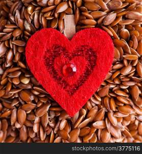 diet healthcare concept. Brown raw flax seeds linseed and red heart symbol. Healthy food for preventing heart diseases. Flaxseeds are full of omega-3 fatty acids.