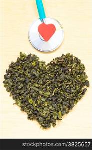 Diet healthcare concept. Green tea heart shaped stethoscope on wooden surface. Healthy food drink for lower heart disease risk