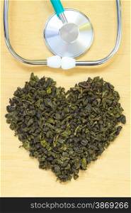 Diet healthcare concept. Green tea heart shaped stethoscope on wooden surface. Healthy food drink for lower heart disease risk