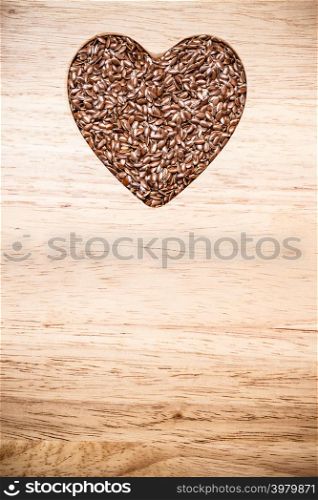 Diet healthcare healthy food. Raw flax seeds linseed heart shaped on wooden board background.