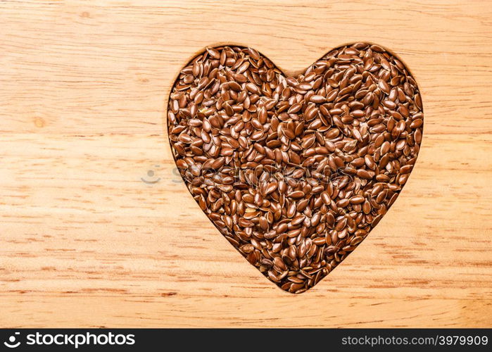 Diet healthcare healthy food. Raw flax seeds linseed heart shaped on wooden board background.