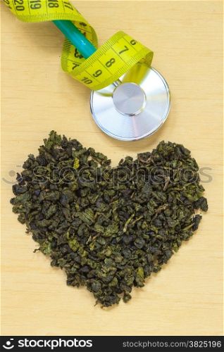 Diet healthcare weight loss concept. Green tea heart shaped stethoscope on wooden surface. Healthy food drink for lower heart disease risk
