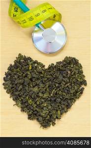 Diet healthcare weight loss concept. Green tea heart shaped stethoscope on wooden surface. Healthy food drink for lower heart disease risk