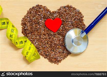 Diet healthcare weight reduction concept. Flax seeds linseed heart shaped stethoscope and measuring tape. Healthy food for preventing heart diseases, overweight.