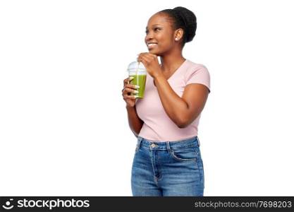 diet, healthy eating and detox concept - happy smiling young african american woman drinking green vegetable juice or smoothie from plastic cup with paper straw over white background. happy african american woman drinking green juice