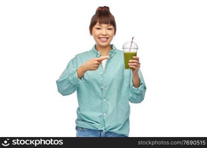 diet, healthy eating and detox concept - happy smiling young asian woman drinking green vegetable juice or smoothie from plastic cup with paper straw over white background. happy smiling asian woman with can drink