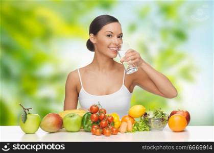 diet, healthy eating and people concept - woman with food on table drinking water over green natural background. woman with healthy food on table drinking water. woman with healthy food on table drinking water