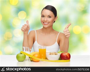 diet, healthy eating, slimming, gesture and people concept - happy smiling woman with food and measure tape showing thumbs up over green summer lights background. woman with food and measure tape showing thumbs up