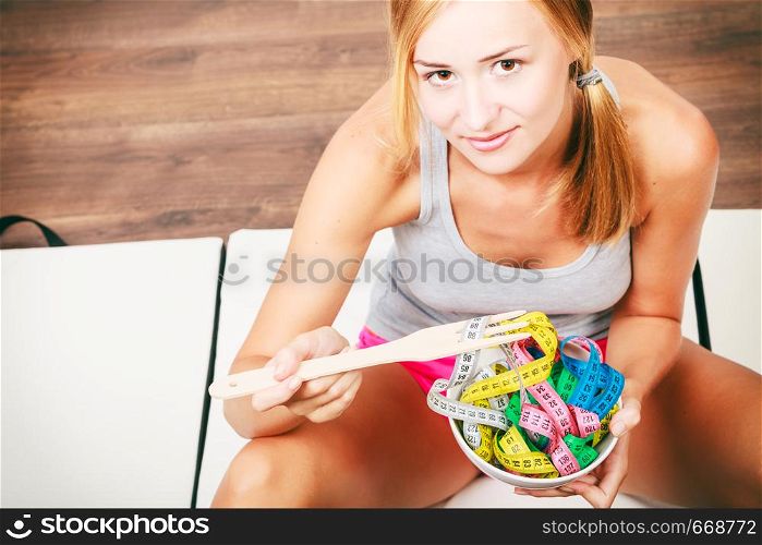 Diet, healthy eating, weight loss and slim body concept. Fit fitness girl holding bowl with many colorful measuring tapes
