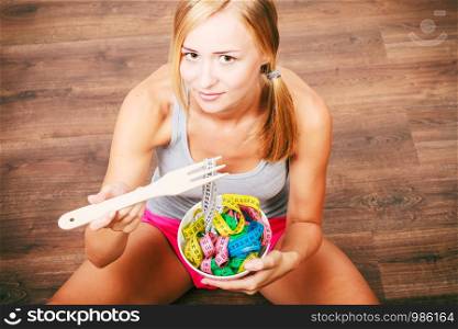 Diet, healthy eating, weight loss and slim body concept. Fit fitness girl holding bowl with many colorful measuring tapes