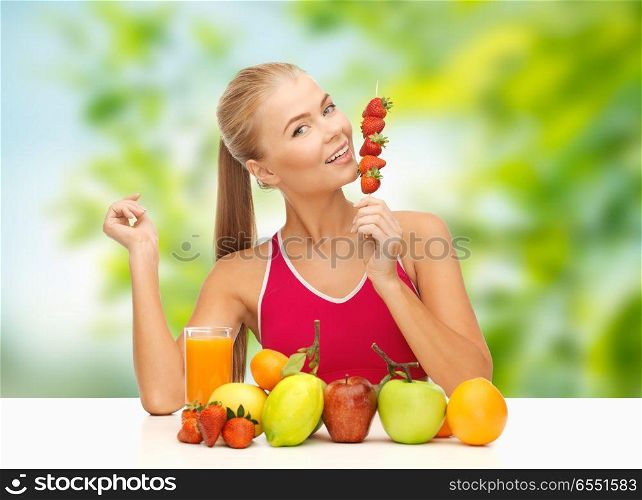 diet, healthy food and people concept - woman with fruits and juice eating strawberry over green natural background. woman with fruits and juice eating strawberry. woman with fruits and juice eating strawberry