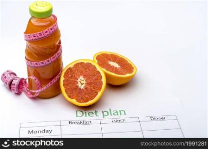 Diet plan and bottle of grapefruit juice with fresh grapefruit on white background. The concept of healthy eating.. Diet plan and bottle of grapefruit juice with fresh grapefruit on white background.