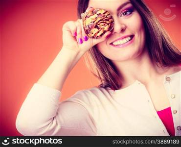 Diet sweet food and people concept. Funny woman holds cake in hand having fun covering her eye with cupcake orange background