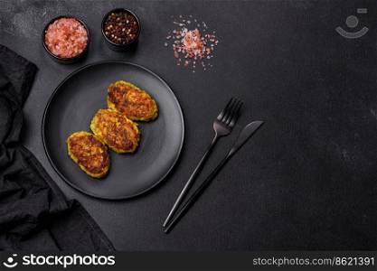 Diet vegetable cutlet from zucchini, carrot, herbs on a black plate on a dark concrete table. Healthy food. Diet vegetable cutlet from zucchini, carrot, herbs on a black plate