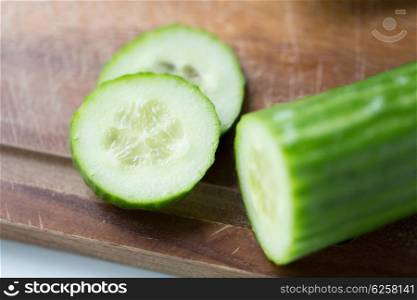 diet, vegetable food, cooking and objects concept - close up of cucumber on wooden cutting board