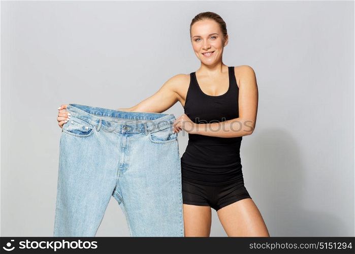 diet, weight loss and people concept - young slim sporty woman with oversize pants. young slim sporty woman with oversize pants