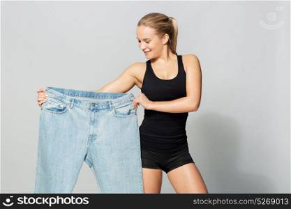 diet, weight loss and people concept - young slim sporty woman with oversize pants. young slim sporty woman with oversize pants
