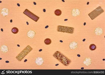 Dietary bars, marmalade, bread rolls and raisins on an orange background. Diet bars, marmalade, bread rolls and raisins.
