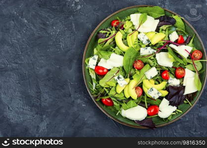 Dietetic salad with fresh lettuce, greens, avocado, tomatoes and cheeses. Copy space. Fresh vegetable salad with greens and mozzarella