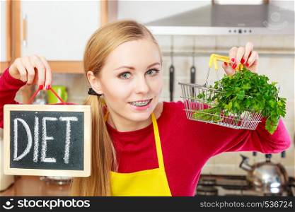 Dieting and detoxing, weight loss concept. Happy woman holding board with diet sign and shopping basket with leafy vegetable inside.. Woman holding diet sign and shopping basket with
