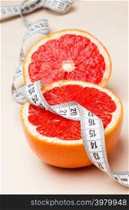 Dieting concept. Closeup grapefruit fruit with measuring tape on table