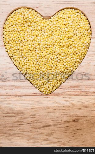 Dieting concept. Millet groats heart shaped on wooden surface. Healthy food help lower cholesterol.