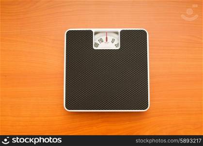 Dieting concept with scales on the wooden floor