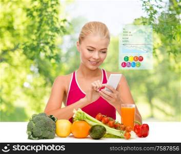 dieting, food, healthcare and technology concept - happy smiling sporty woman with fruits and vegetables counting calories in smartphone over green natural background. woman with vegetables pointing at smartphone