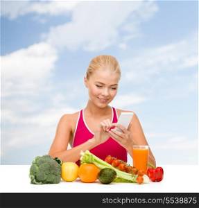 dieting, food, healthcare and technology concept - smiling sporty woman with fruits and vegetables counting calories in smartphone