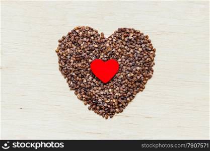 Dieting healthcare concept. buckwheat groats heart shaped on wooden surface. Healthy food gluten-free