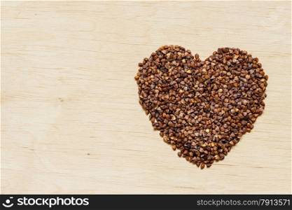 Dieting healthcare concept. buckwheat groats heart shaped on wooden surface. Healthy food gluten-free