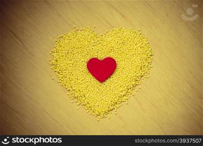 Dieting healthcare concept. Millet groats heart shaped on wooden surface. Healthy food gluten-free and highly alkaline.