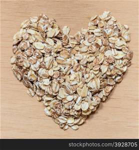 Dieting healthcare concept. Oat cereal heart shaped on wooden surface. Healthy food for lowering cholesterol, protect heart.