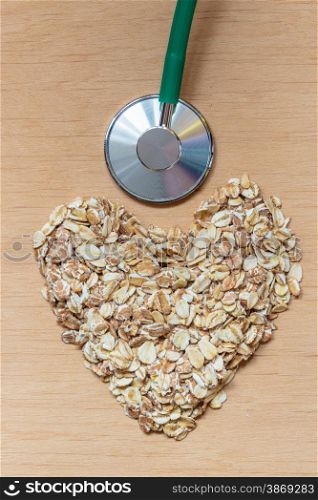 Dieting healthcare concept. Oat cereal heart shaped, stethoscope on wooden surface. Healthy food for lowering cholesterol, protect heart.
