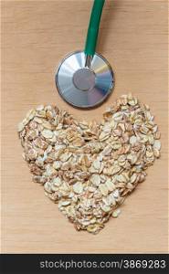Dieting healthcare concept. Oat cereal heart shaped, stethoscope on wooden surface. Healthy food for lowering cholesterol, protect heart.